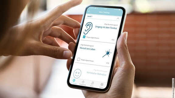 Frau mit Handy in der Hand klickt sich durch die Kalmeda Tinnitus-App.